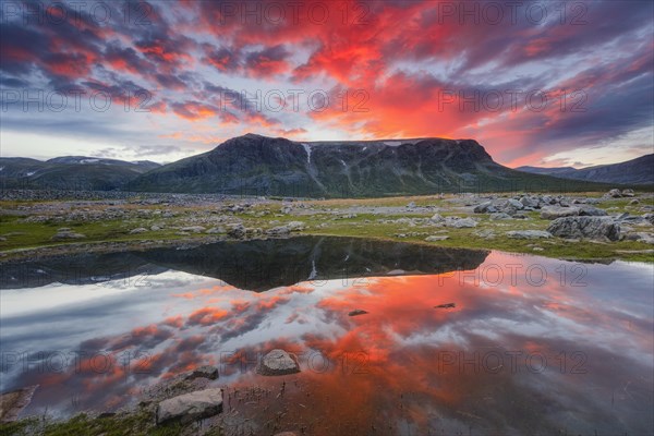 Mountain range reflected in the lake in evening mood with red clouds