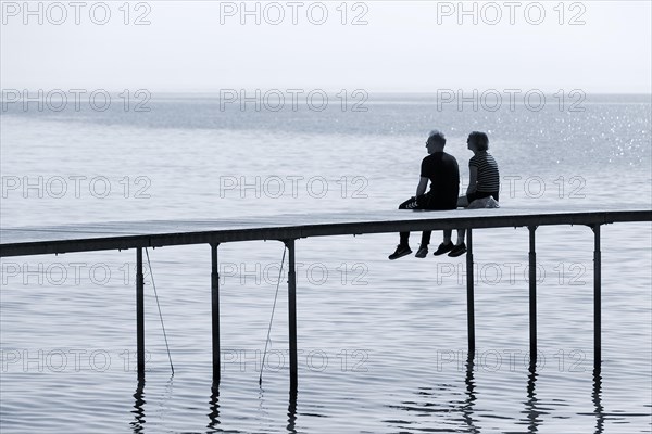Couple sitting on bathing jetty