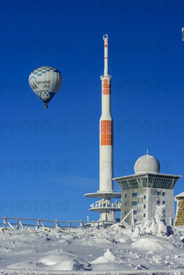 Hot-air balloon with transmitter mast and Brocken hostel on the winter snow-covered Brocken