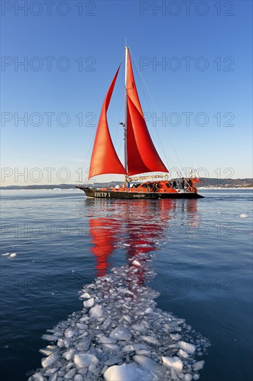 Red sailing boat in drift ice