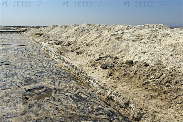 Harvested rock salt at the edge of an evaporation basin of a salt works