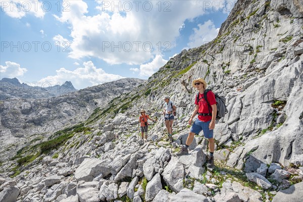 Three hikers in a landscape of washed-out karst rocks