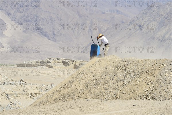 Worker with wheelbarrow in the ruins of Caral
