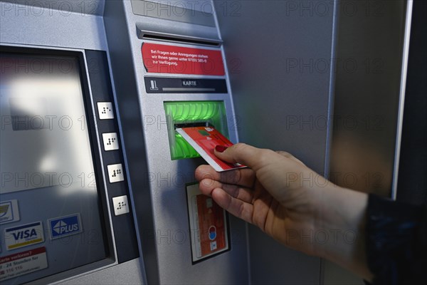 Woman introduces ec-card at the cash dispenser of a savings bank