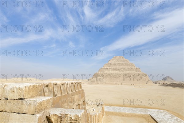 Wall engraved with images of cobra snakes next to stepped pyramid