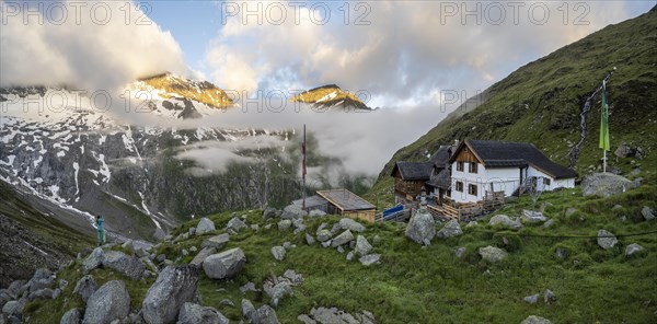 Hiker looks at mountain peaks with last sunlight