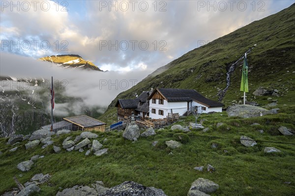 Furtschaglhaus with mountain peaks in the last sunlight and clouds