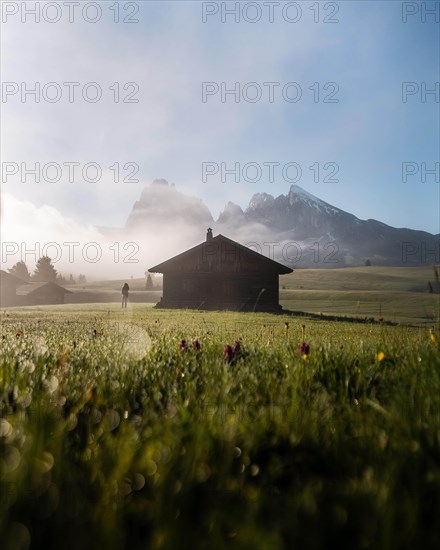 Woman looking on foggy meadow next to hut