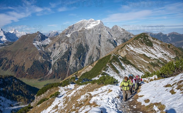 Three hikers on a hiking trail with snow in autumn