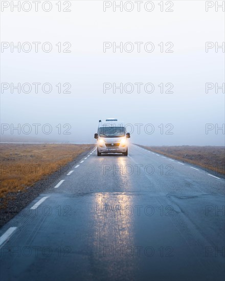 Campervan with bright lights on a road near the North Cape