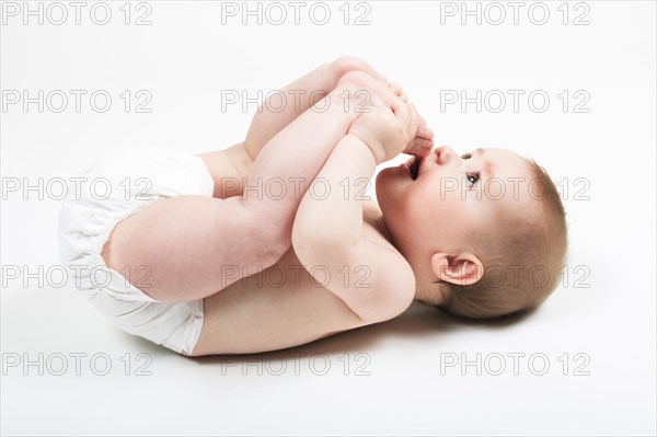 Baby lies on back and plays with his feet