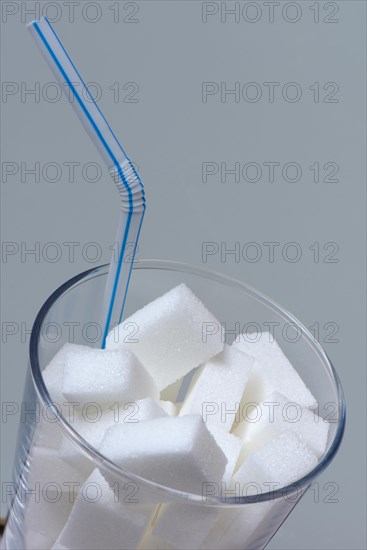 Sugar cubes in drinking glass with straw