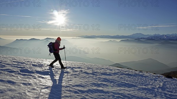 Hiker descending over snowfield from Monte Lema