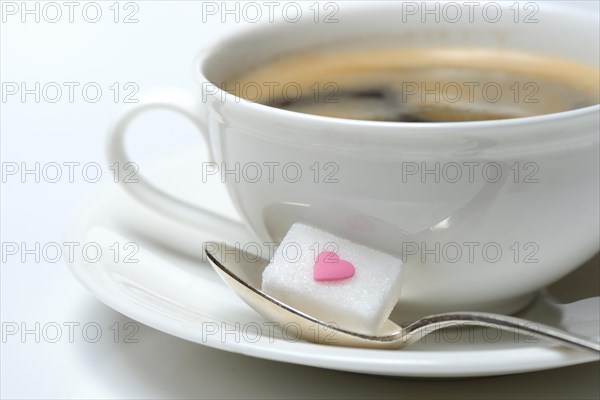 Sugar cube with sugar heart and cup of coffee