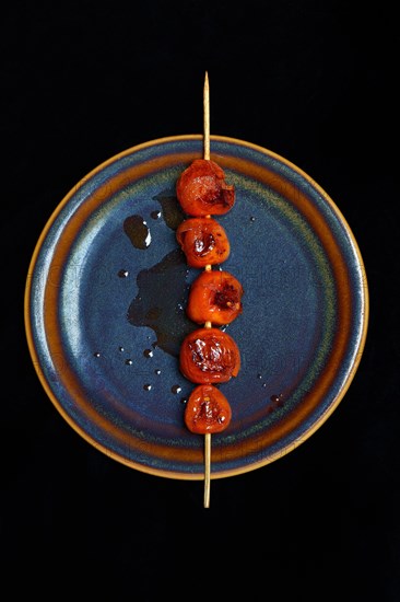 Roasted cherry tomatoes on skewer on plate