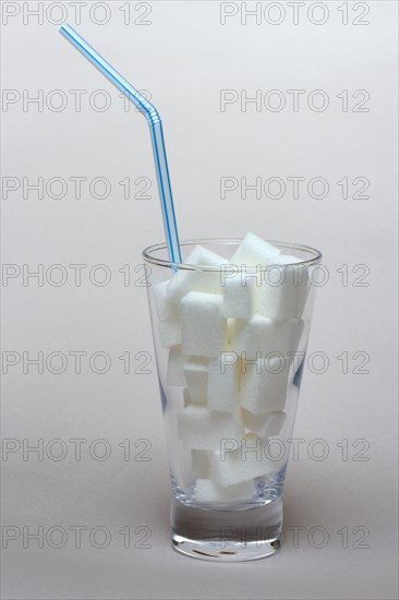 Sugar cubes in drinking glass with straw