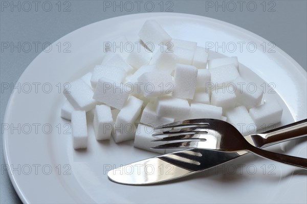 Sugar cubes on plate with cutlery