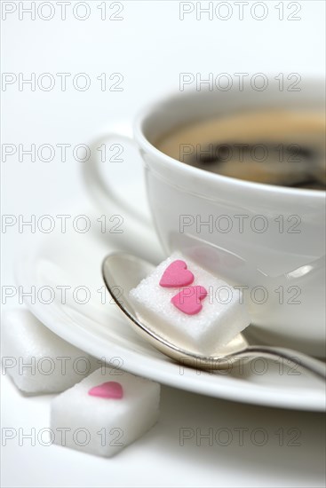 Sugar cube with sugar heart and cup of coffee