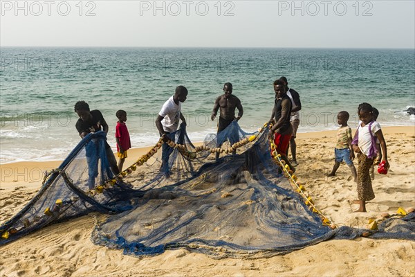 Local fishermen pulling their nets on a beach in Robertsport