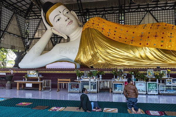 Pilgrims praying before a reclining buddha