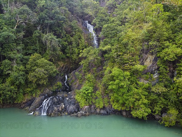 Aerial of a waterfall dropping right in the ocean on Dome island