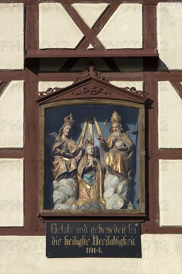 Figures of the Trinity in a glass shrine in the facade of a farmhouse