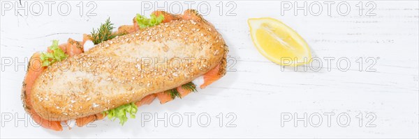 Sandwich baguette wholemeal roll topped with salmon fish banner text free space from top on