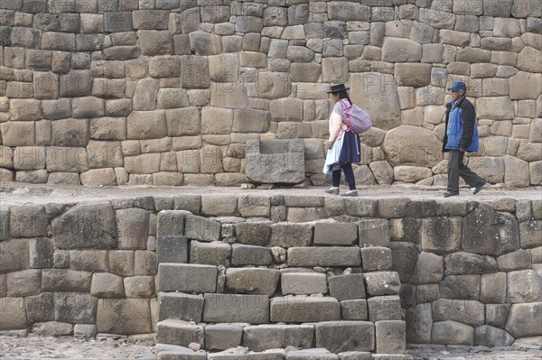 Old indigenous couple walking on the ruins of the Inca Temple of the Sun