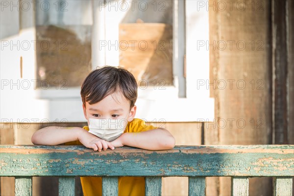 Young Mixed Race Chinese and Caucasian Boy Playing Alone Wearing Medical Face Mask Outside