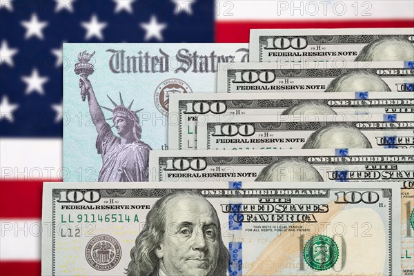 Six hundred dollars and United States IRS stimulus check resting on american flag