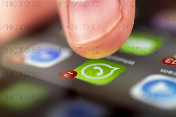 Finger tapping on screen with app icons of messenger services and social networks