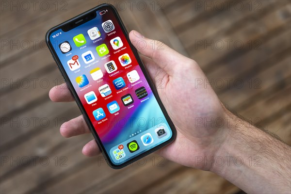 Hand haelt iPhone 11 Pro mit Homescreen