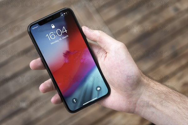 Hand haelt iPhone 11 Pro mit Lockscreen