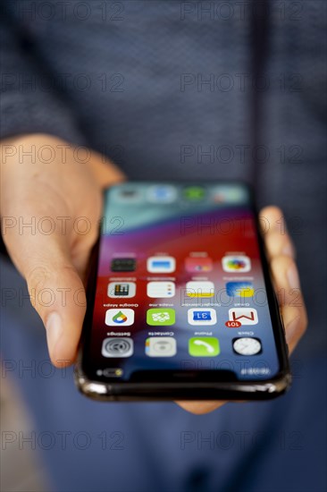 Hand haelt iPhone 11 Pro mit Homescreen
