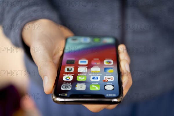 Hand haelt iPhone 11 Pro mit Homescreen