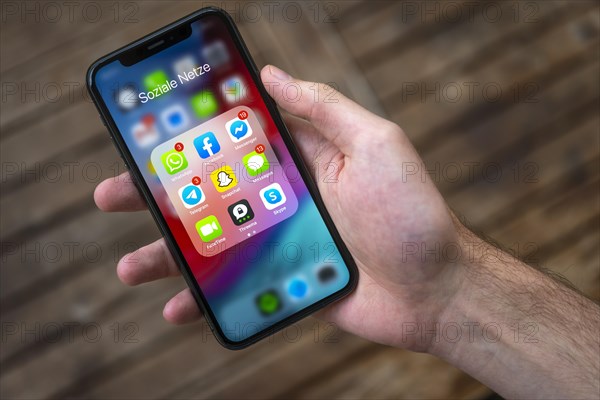 Hand haelt iPhone 11 Pro mit App-Icons von Messenger Diensten und Sozialen Netzwerken