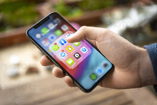 Hand haelt iPhone 11 Pro mit App-Icons von Messenger Diensten und Sozialen Netzwerken