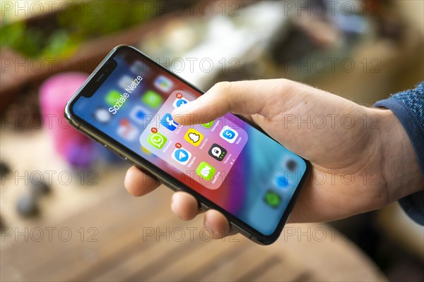 Hand haelt iPhone 11 Pro mit App-Icons von Messenger Diensten und Sozialen Netzwerken