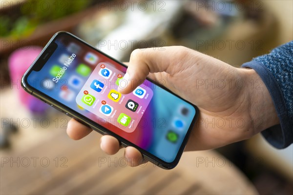 Hand haelt iPhone 11 Pro mit App-Icons von Messenger Diensten und Sozialen Netzwerken