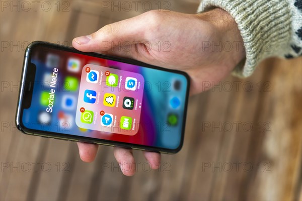 Hand haelt iPhone 11 Pro mit App-Icons von Messenger Diensten und Sozialen Netzwerken