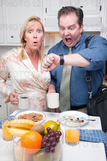 Late for work stressed couple checking time in kitchen