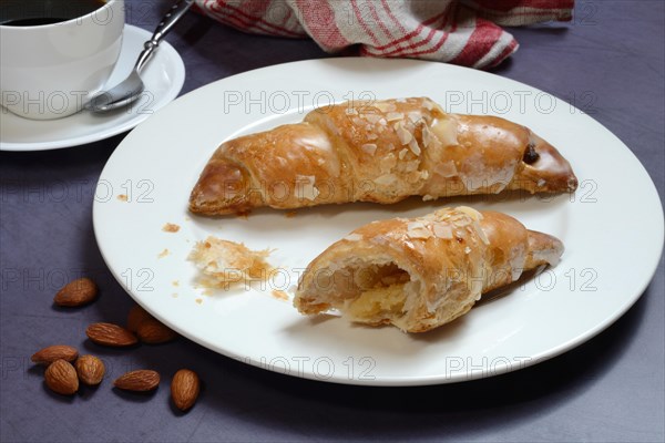 Almond croissant on plate with coffee cup