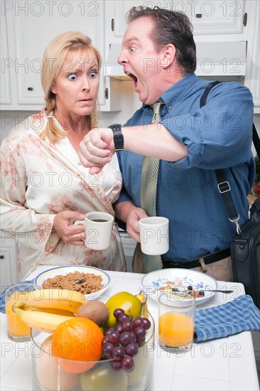 Late for work stressed couple checking time in kitchen
