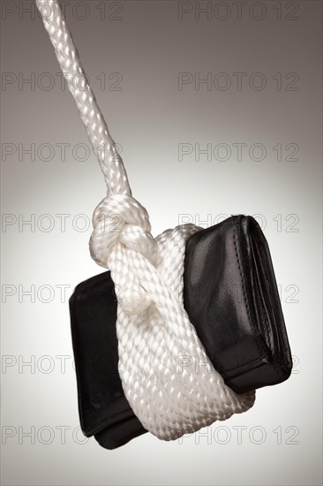 Tied up and hanging wallet on a spot lit background