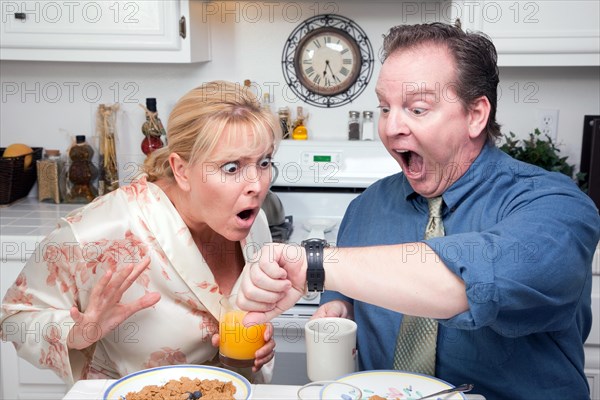 Late for work stressed couple checking time in kitchen
