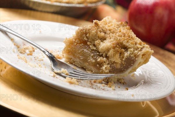 Half eaten apple pie slice with crumb topping and fork
