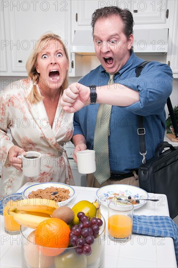 Late for work stressed couple checking time in kitchen