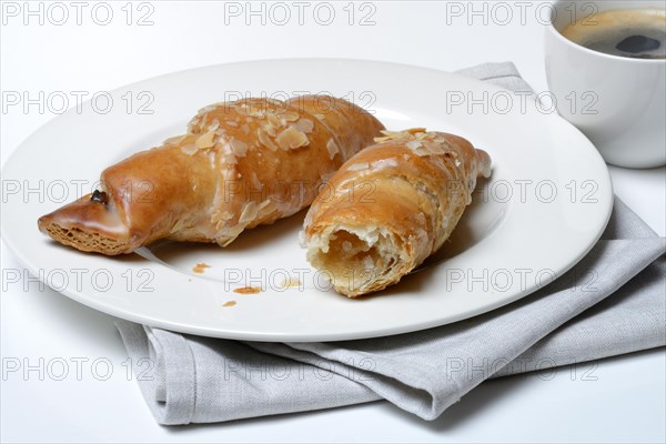 Almond croissant on plate with coffee cup