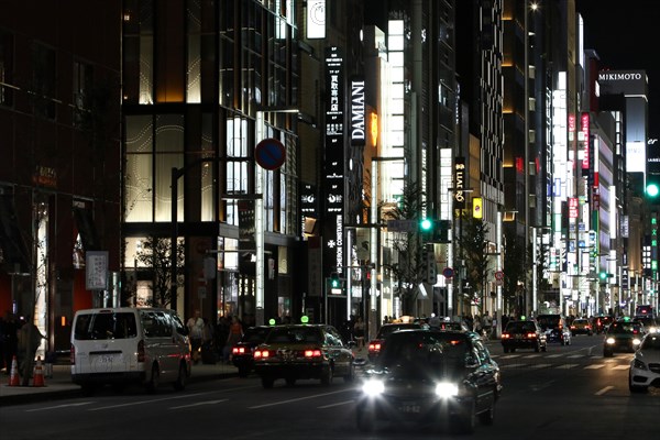 Illuminated street with neon lights and cars in traffic in Ginza district