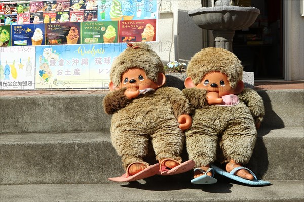 Two large Monchichi puppets on the stairs in front of a souvenir shop